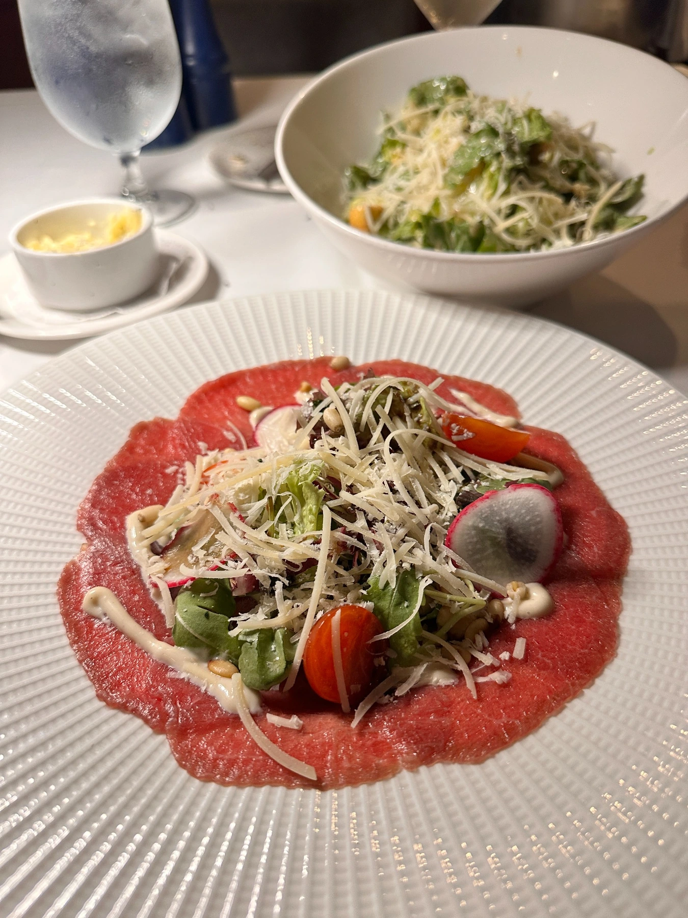 Original carpaccio photograph with a salad bowl and tableware in the background
