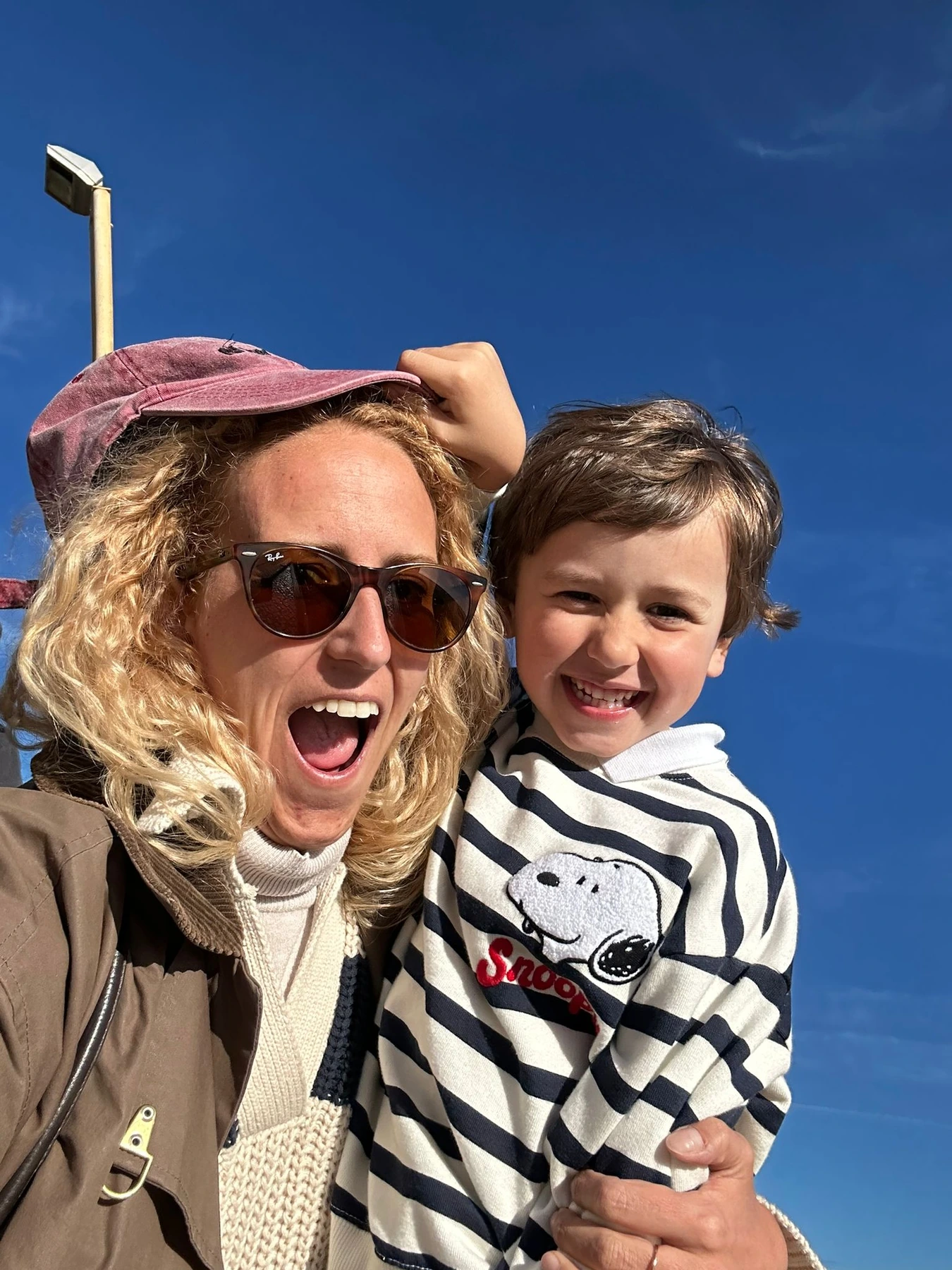 Original outdoor photograph of a woman holding a smiling boy against a blue sky