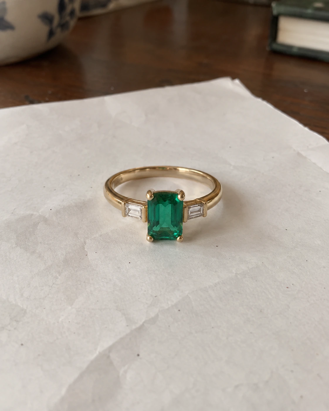 Generated example of an emerald and gold ring photographed casually in uneven light