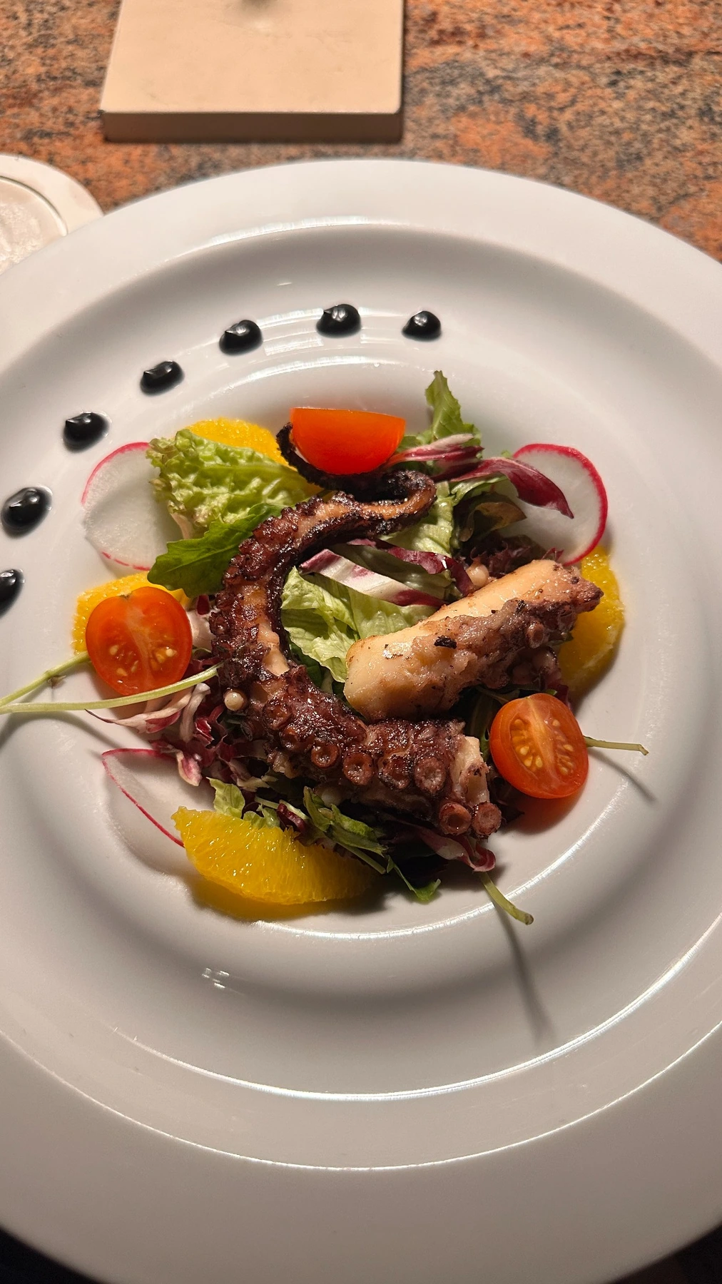 Original restaurant photograph of grilled octopus salad on a white plate