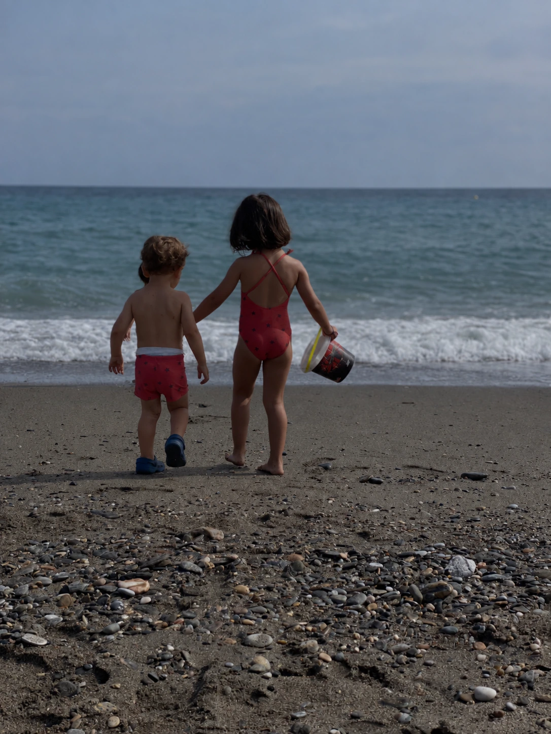 Demonstration before image of two children walking toward the sea, with intentionally reduced exposure and cooler color